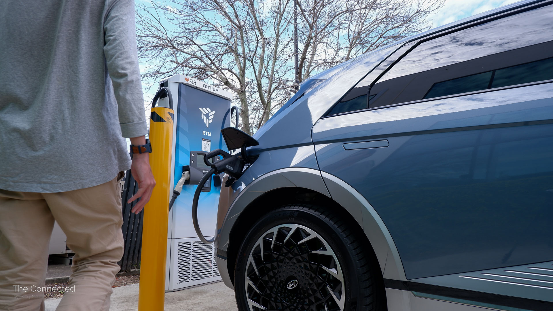Man walks past Hyundai Ioniq 5 plugged-into Tritium DC fast electric car charger
