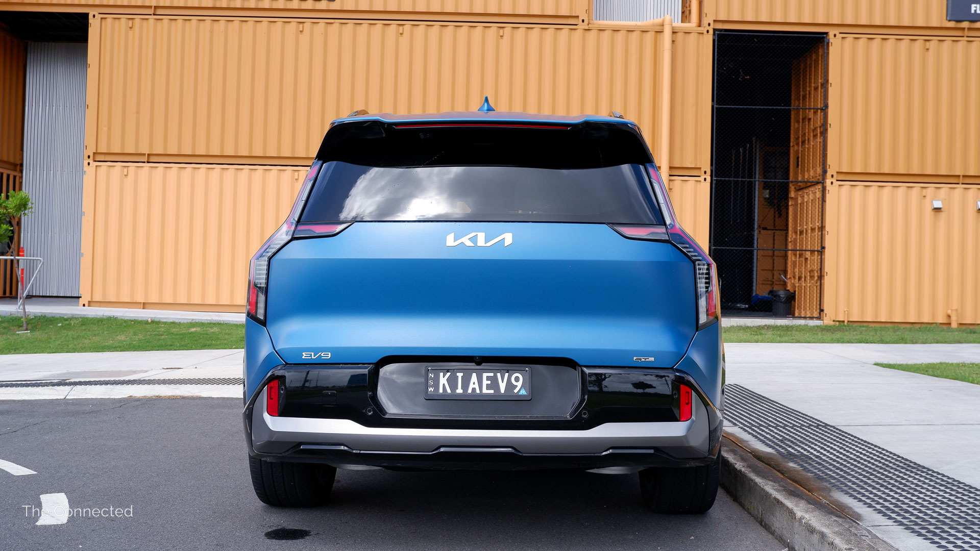 Kia EV9 rear in front of orange shipping containers