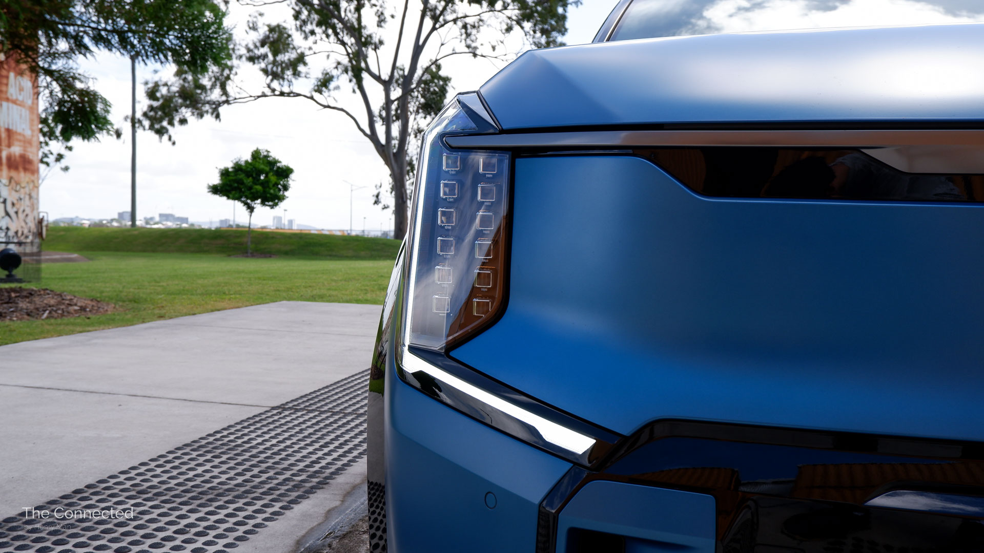 Kia EV9 headlight with green grass and trees behind