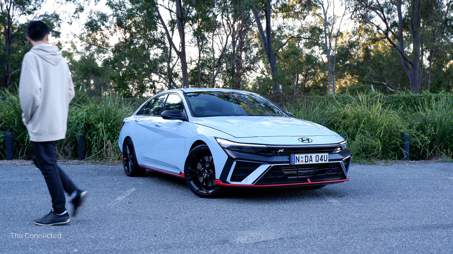 Man walks past Hyundai i30 Sedan N in forest