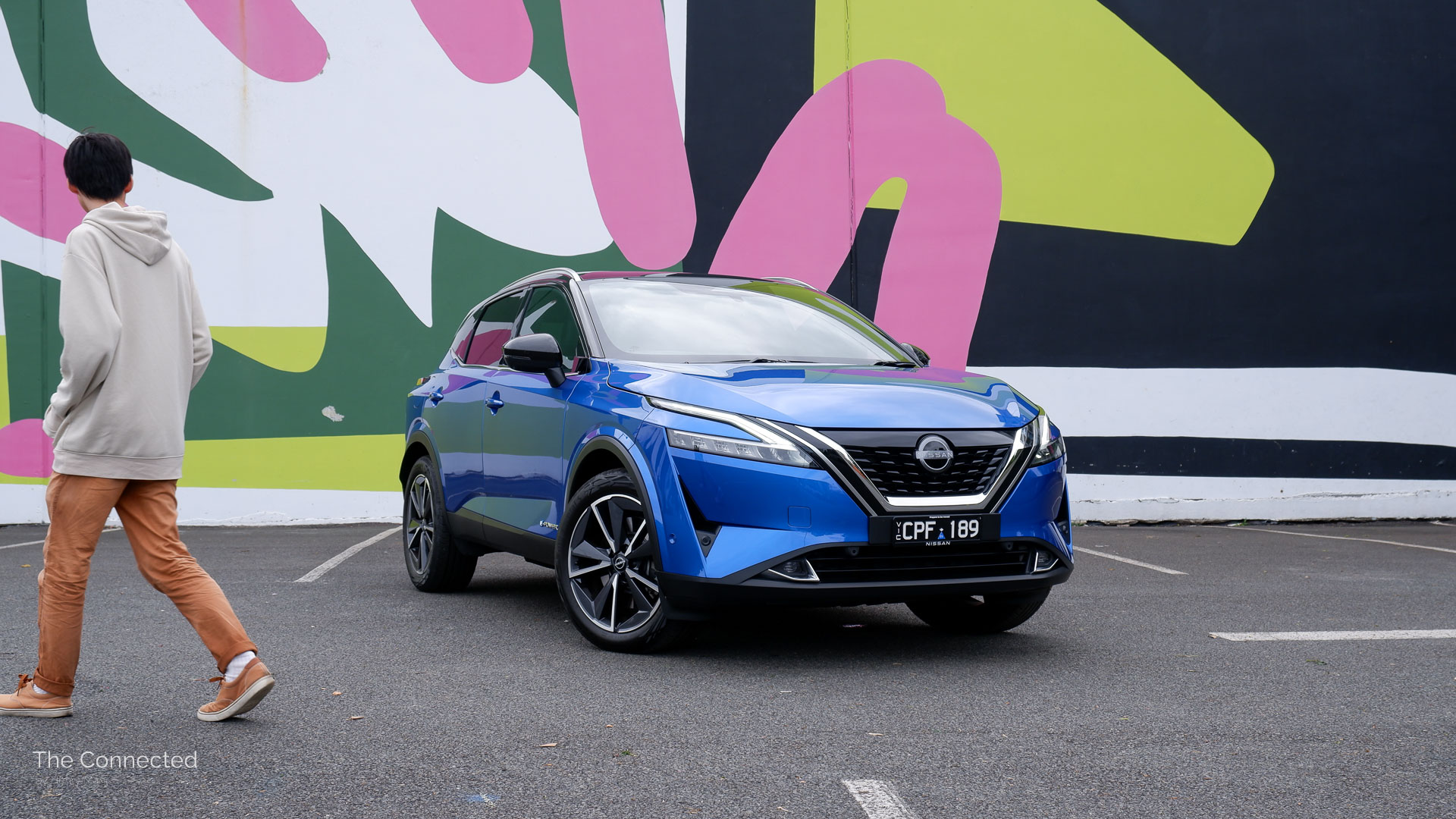 Man walks past 2024 Nissan Qashqai Ti e-Power in front of painted wall
