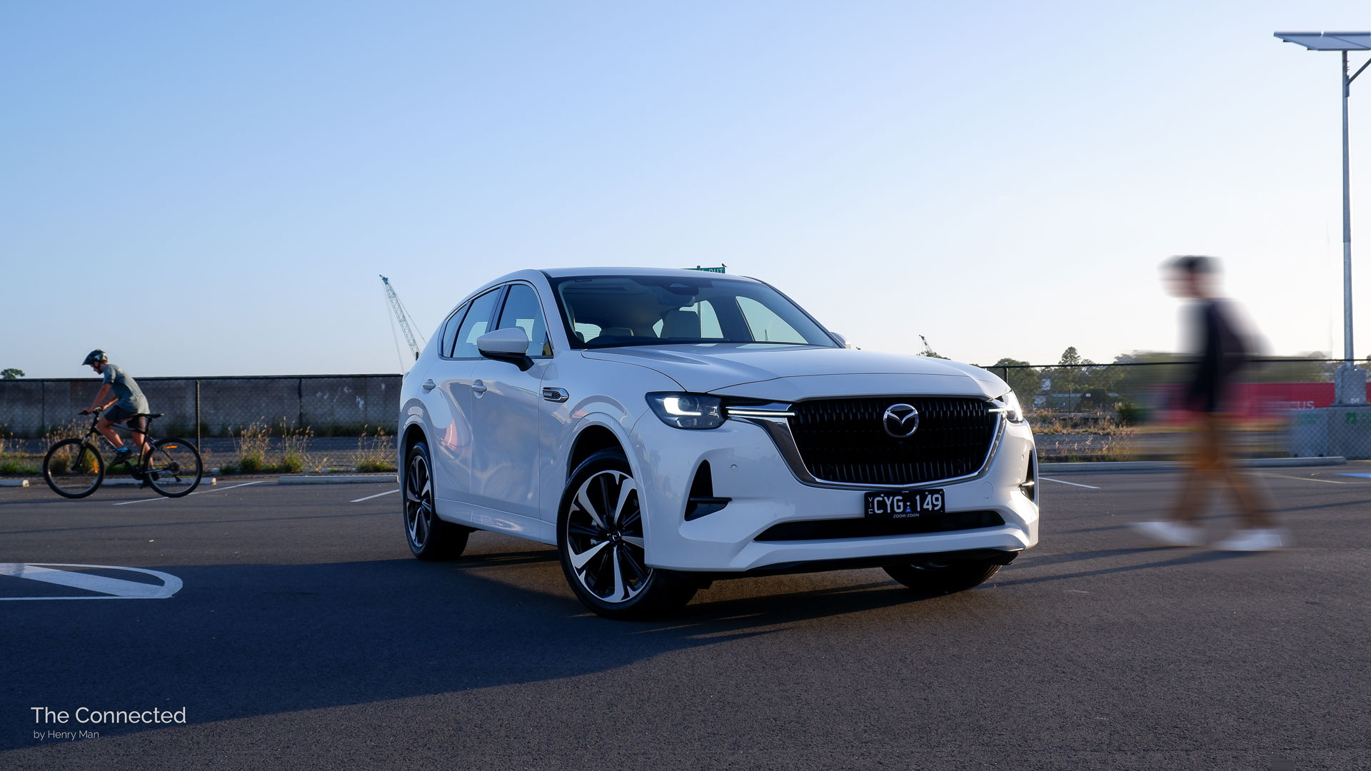 Man and cyclist go past 2024 Mazda CX-60 Azami