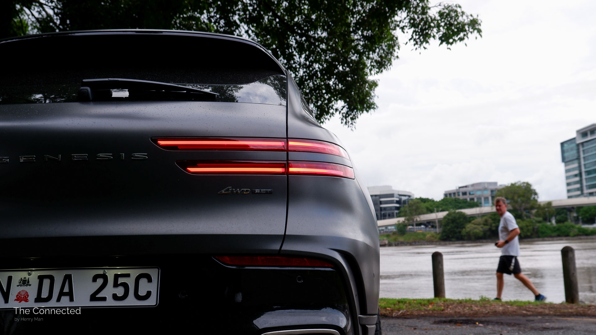 2025 Genesis GV70 Signature Sport tail-light with man looking in the background
