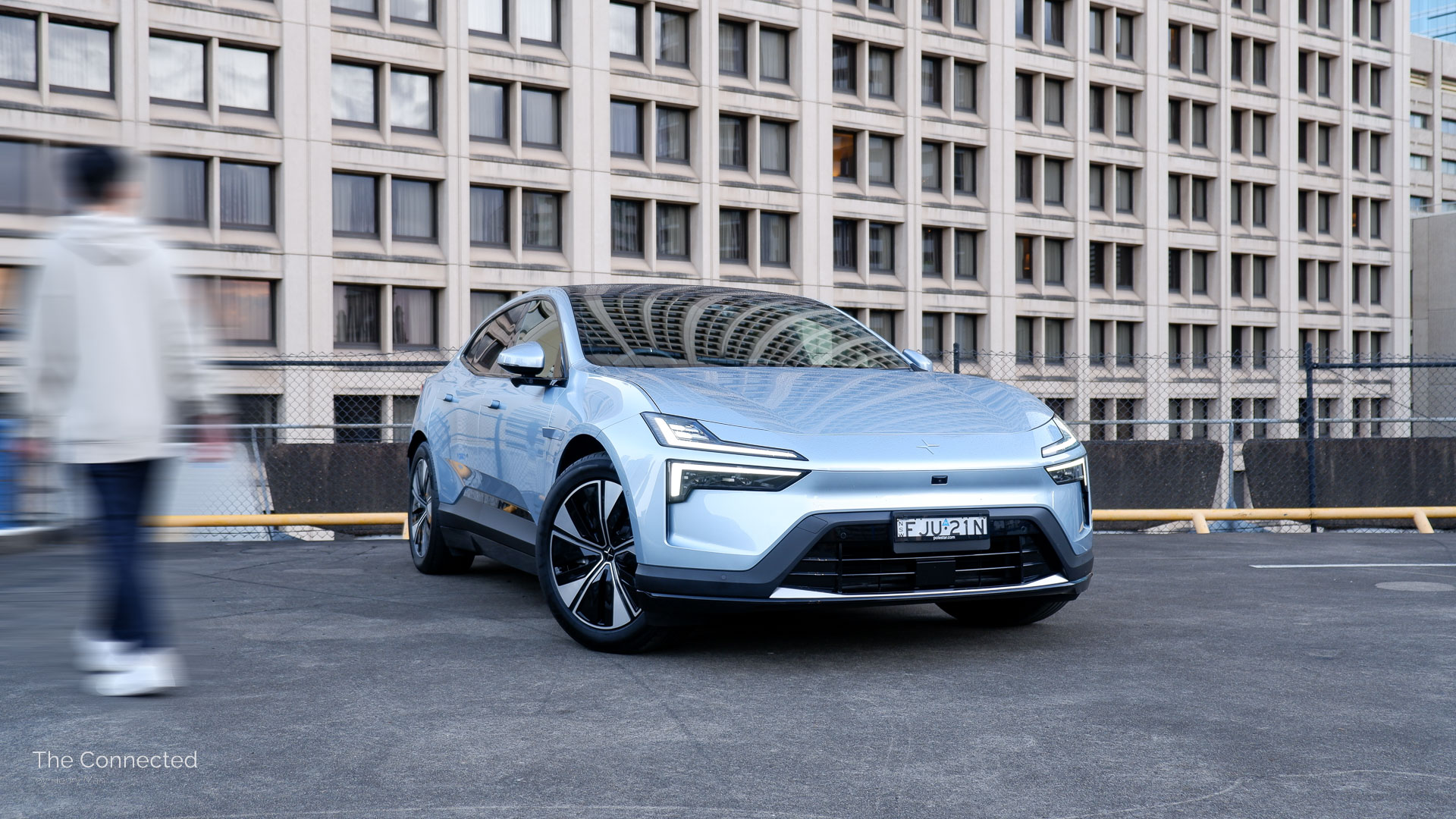 Man walks past 2025 Polestar 4 Long Range Single Motor with city building behind