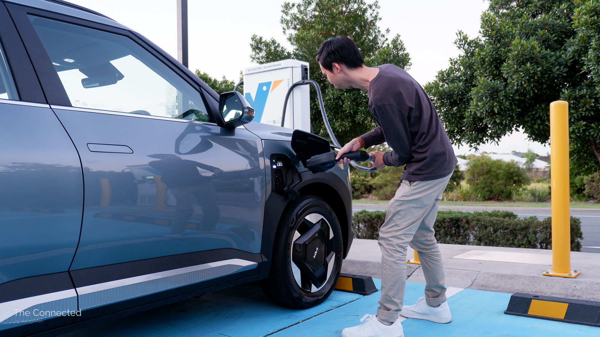 Man stretches cable from public fast charging station to Kia EV5 fender charge port