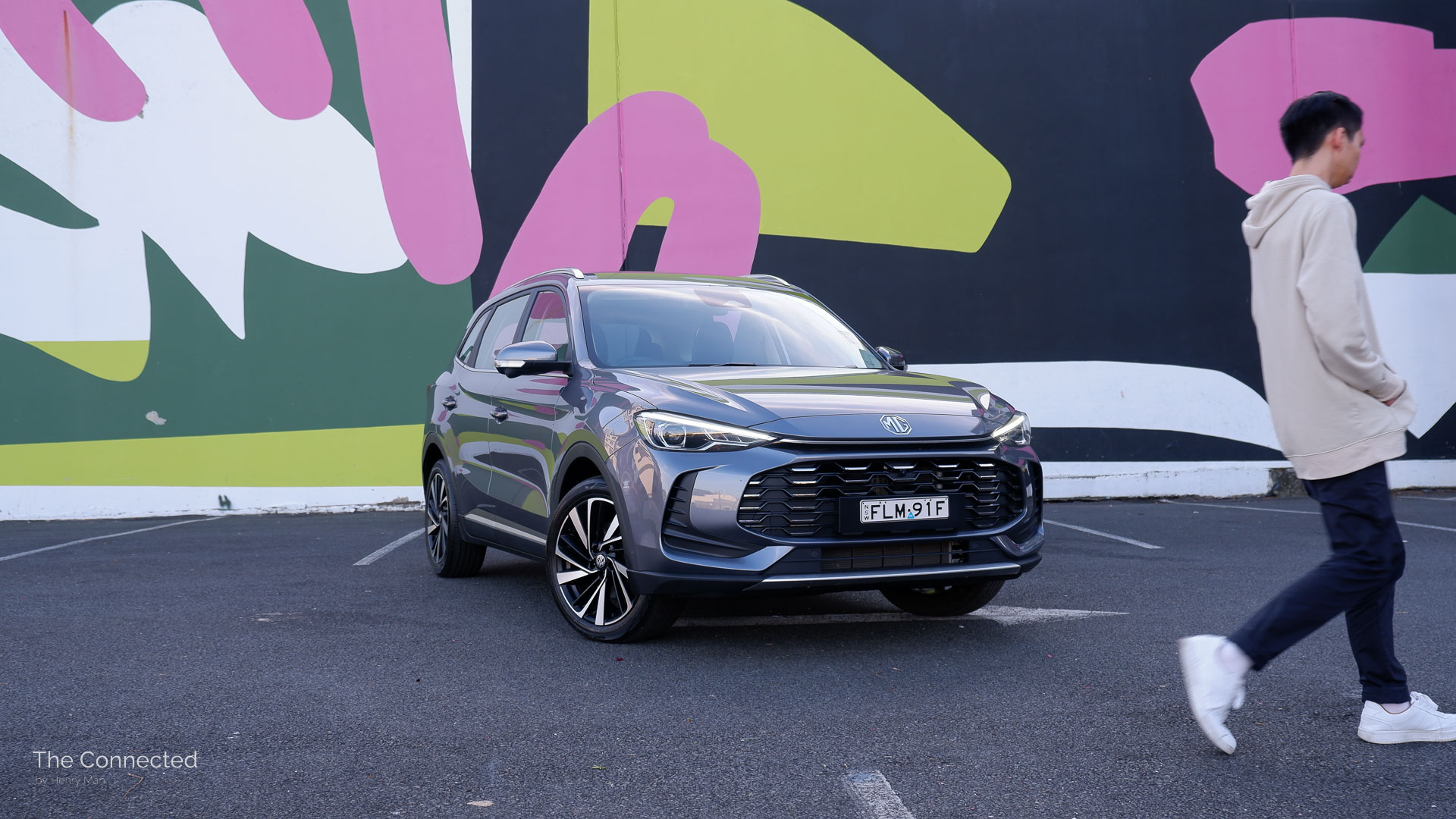 Man walks past 2025 MG ZS Essence Hybrid+ with artwork wall behind