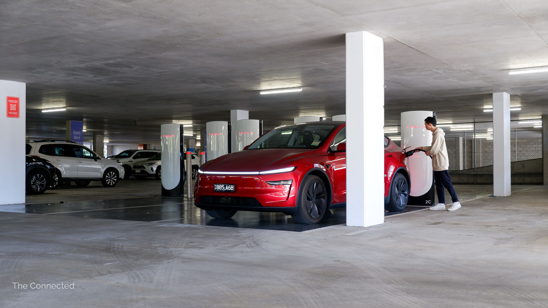 Man plugs in V4 Tesla Supercharger with 2026 Tesla Model Y RWD Ultra Red