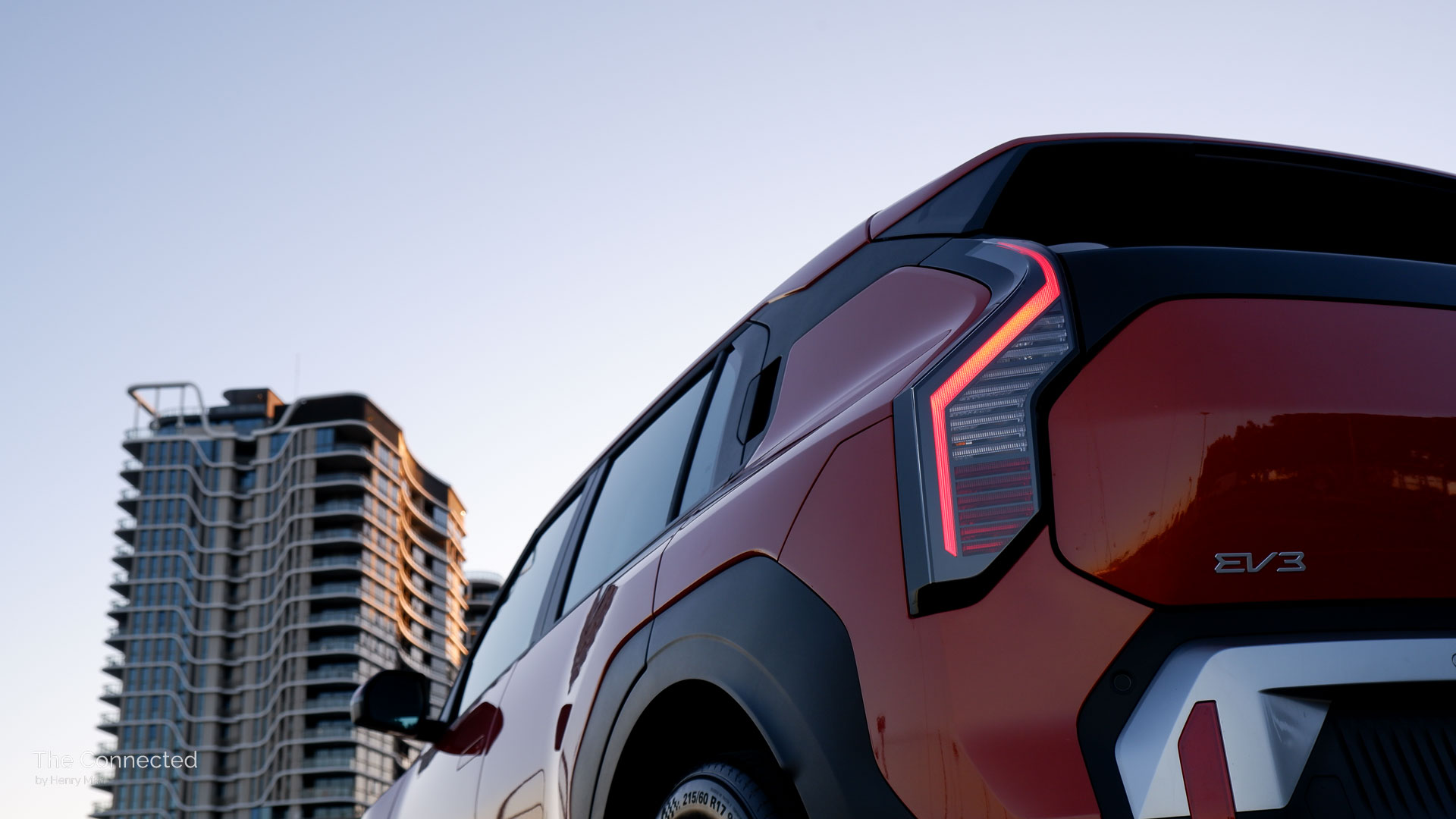2026 Kia EV3 Air rear tail-light strip with city apartment in the background during the sunset