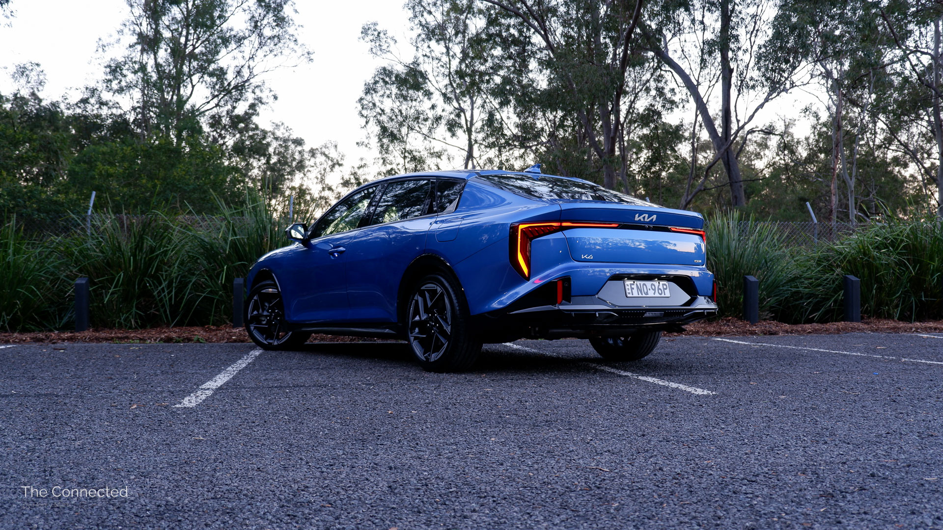 2026 Kia K4 Sedan GT-Line rear-quarter view with sunset forest behind