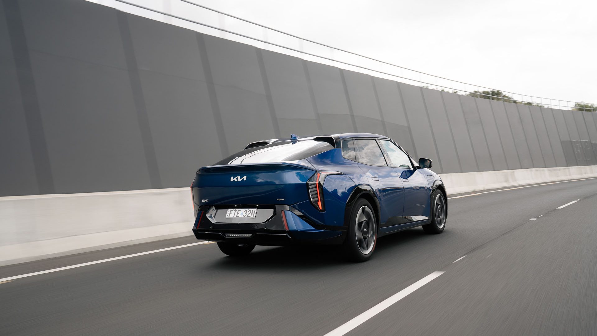 2026 Kia EV4 driving on highway rear-quarter view