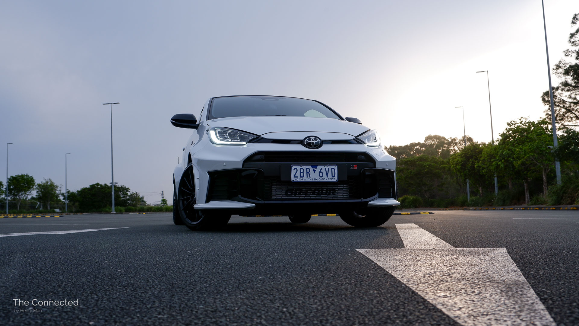 2026 Toyota GR Yaris GT front at a car park with the sunset glowing on a painted arrow on the ground