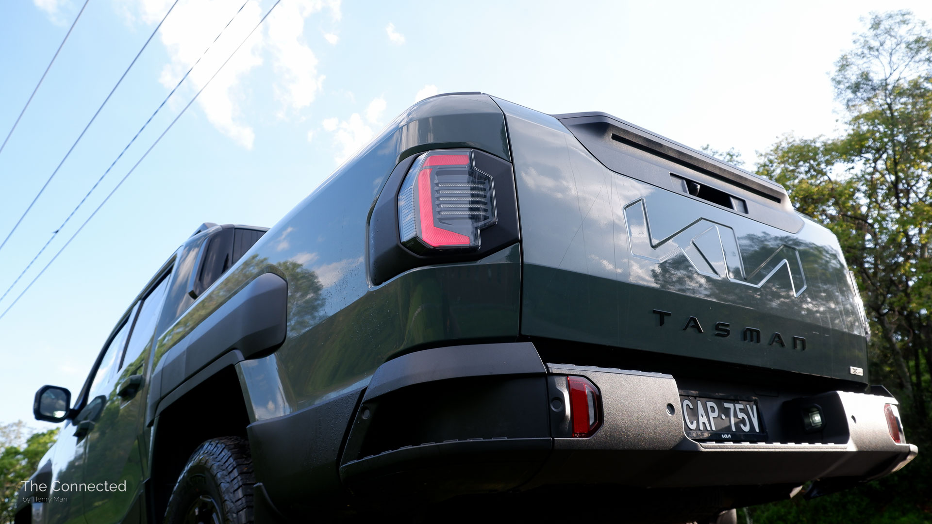 2026 Kia Tasman X-Pro rear tail-light and tailgate with trees and the sky in the background