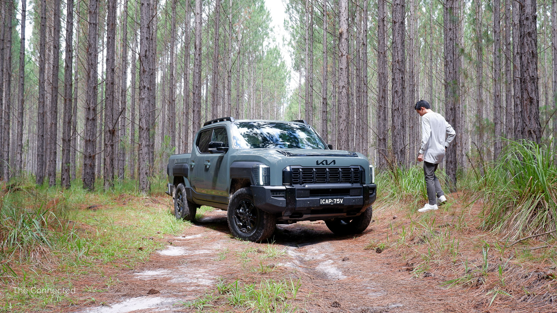 Man walks past the 2026 Kia Tasman X-Pro in the forest