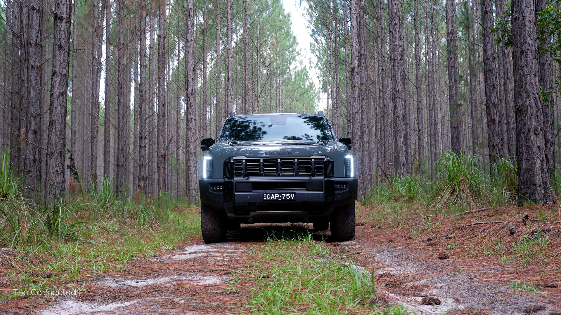 2026 Kia Tasman X-Pro front in a forest trail