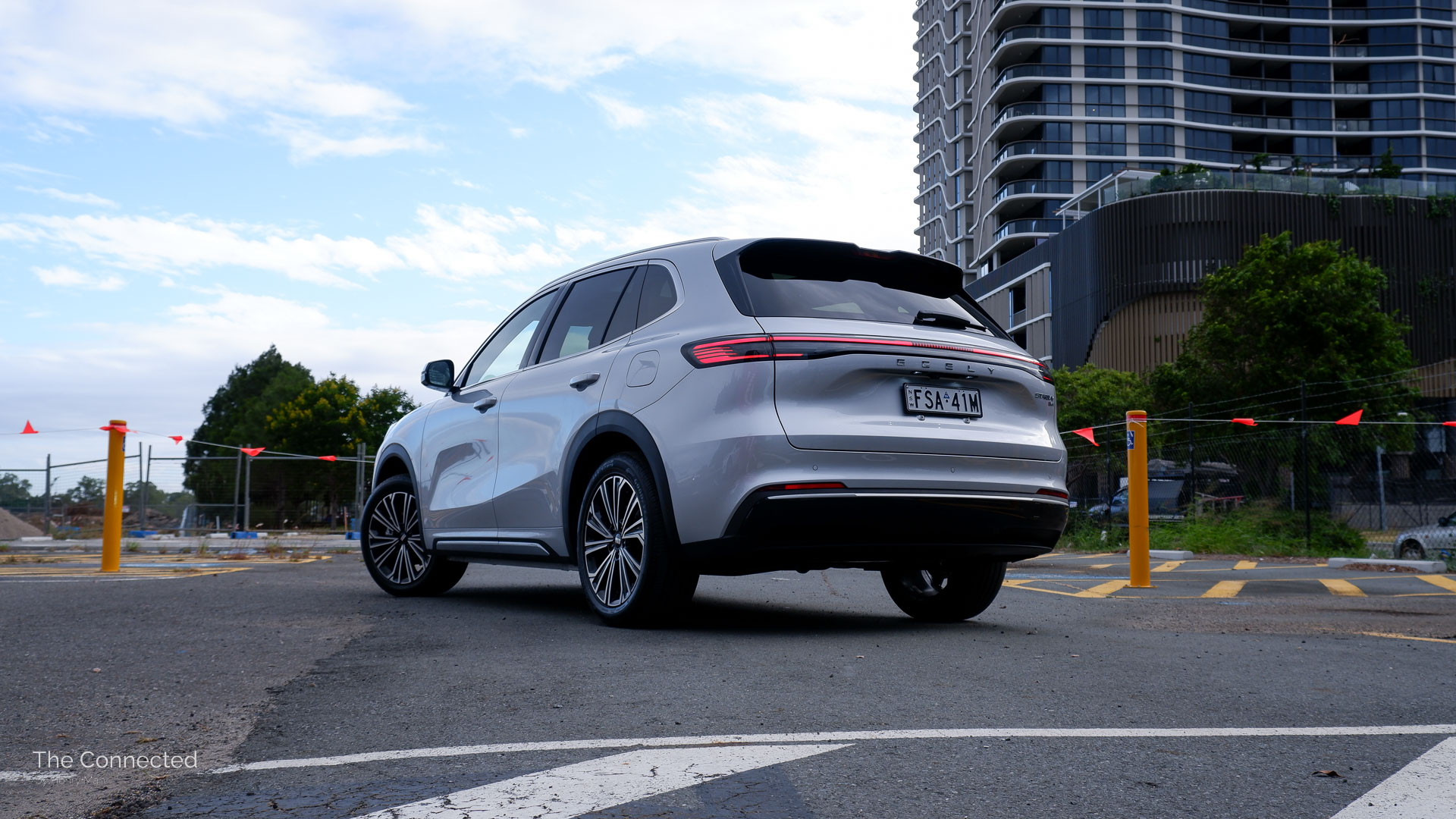 2026 Geely Starray EM-i Inspire rear-quarter view with city apartment in the background