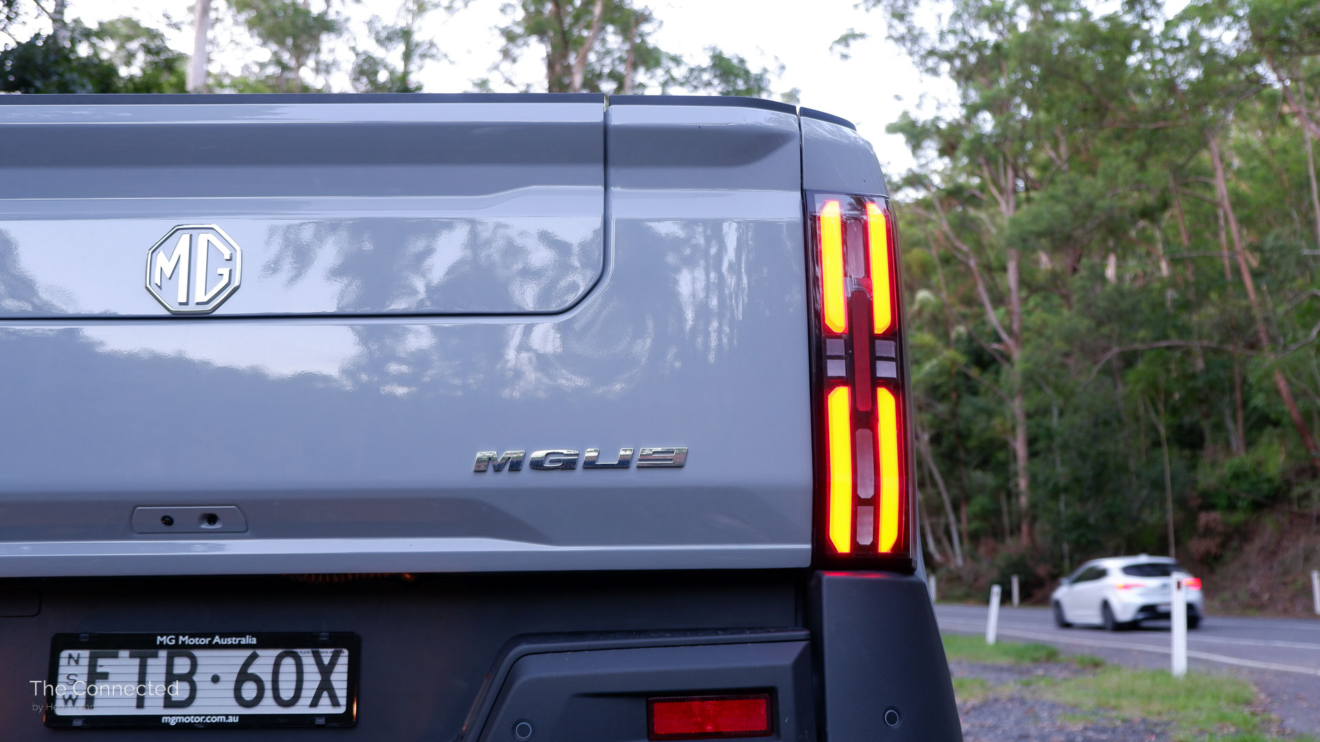 2026 MG U9 Explore Pro rear tail-light and badging with Toyota Corolla passing by in the background