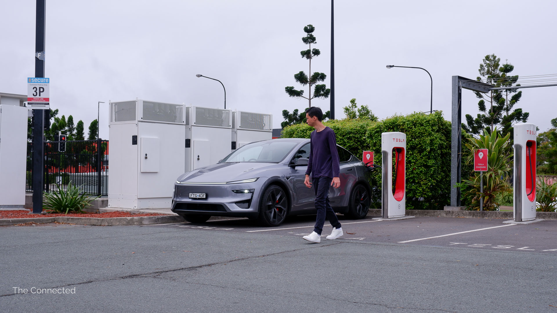 Man walks past the 2026 Tesla Model Y Performance AWD charging at a Tesla Supercharger