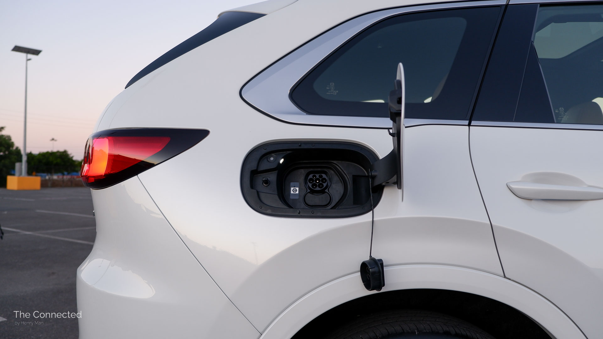 2026 Mazda CX-80 P50e Azami SP open charge port with a cap dangling on the side of the body