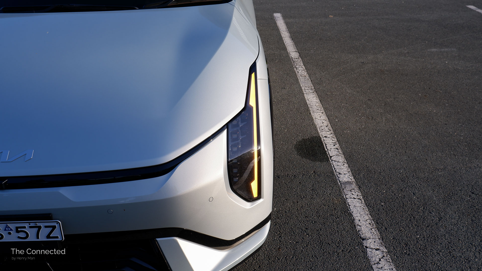 2026 Kia EV4 GT-Line front headlight with turn indicator on in the sunset
