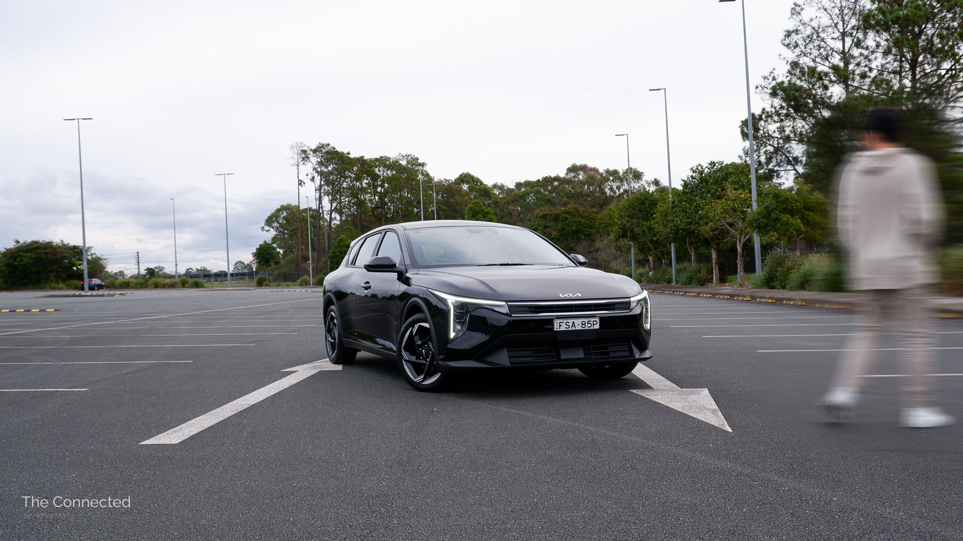 Man walks past the 2026 Kia K4 Hatch Sport at a car park