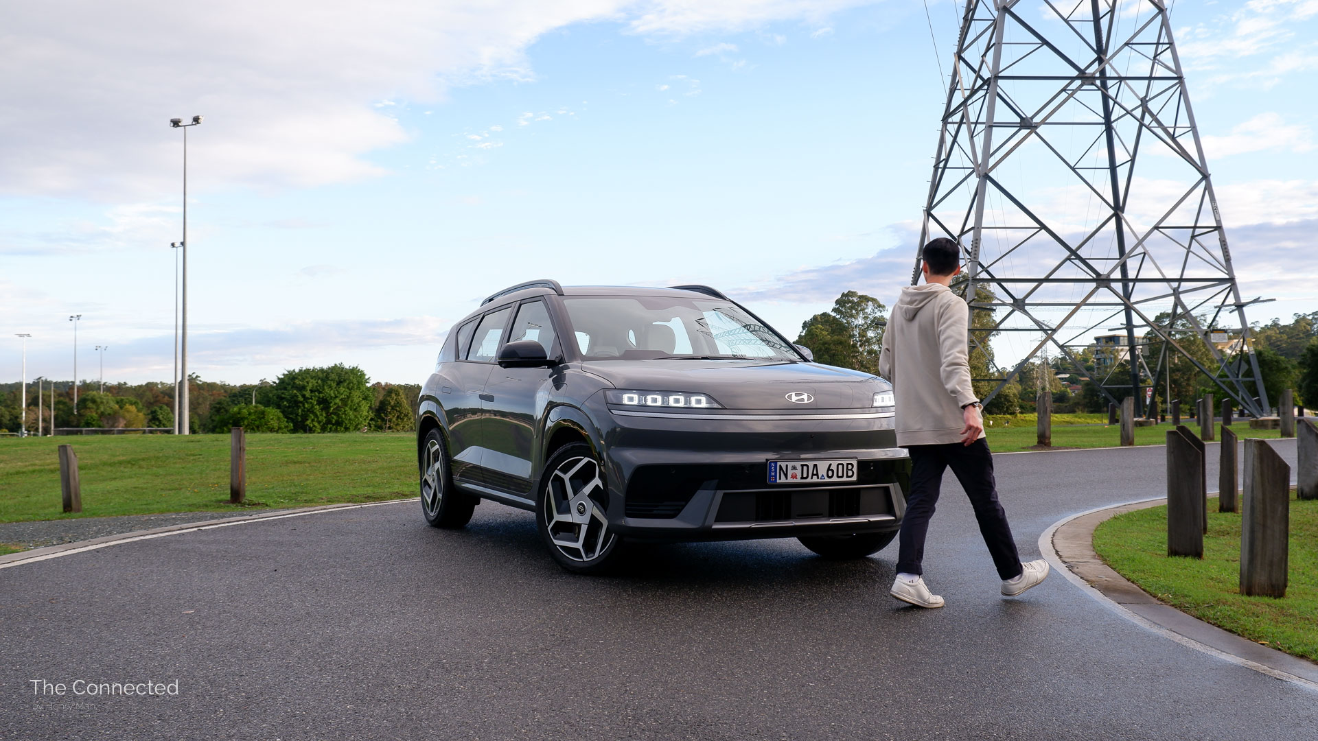 Man walks past the 2026 Hyundai Elexio Elite with a park and electricity transmission tower behind